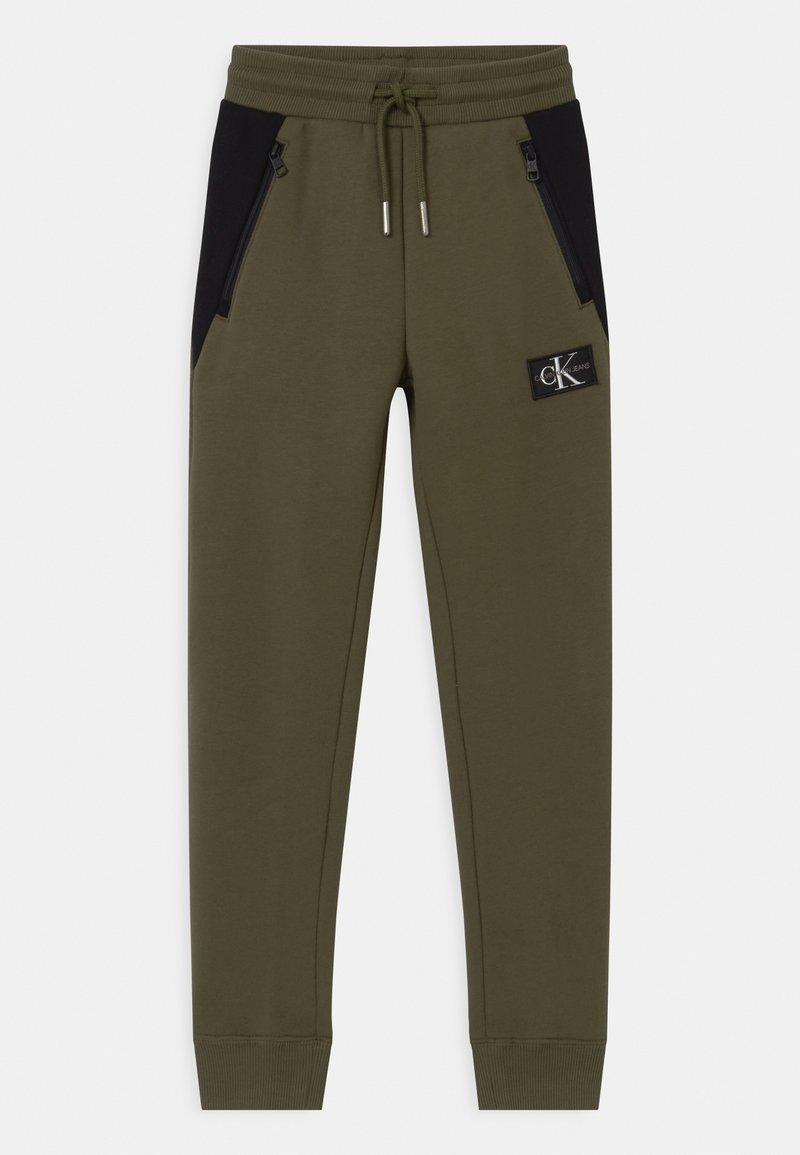 Olivově zelené jogger kalhoty s černými panelovými akcenty, elastickým pasem, nastavitelným stahovacím řemínkem a zipovými bočními kapsami. Obsahuje logovou nášivku.