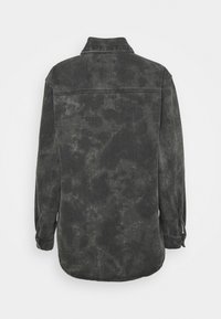 Mörk denimskjorta med en urblekt, texturerad yta. Har klassisk krage, långa ärmar och en rundad nederkant. Endast bakvy.