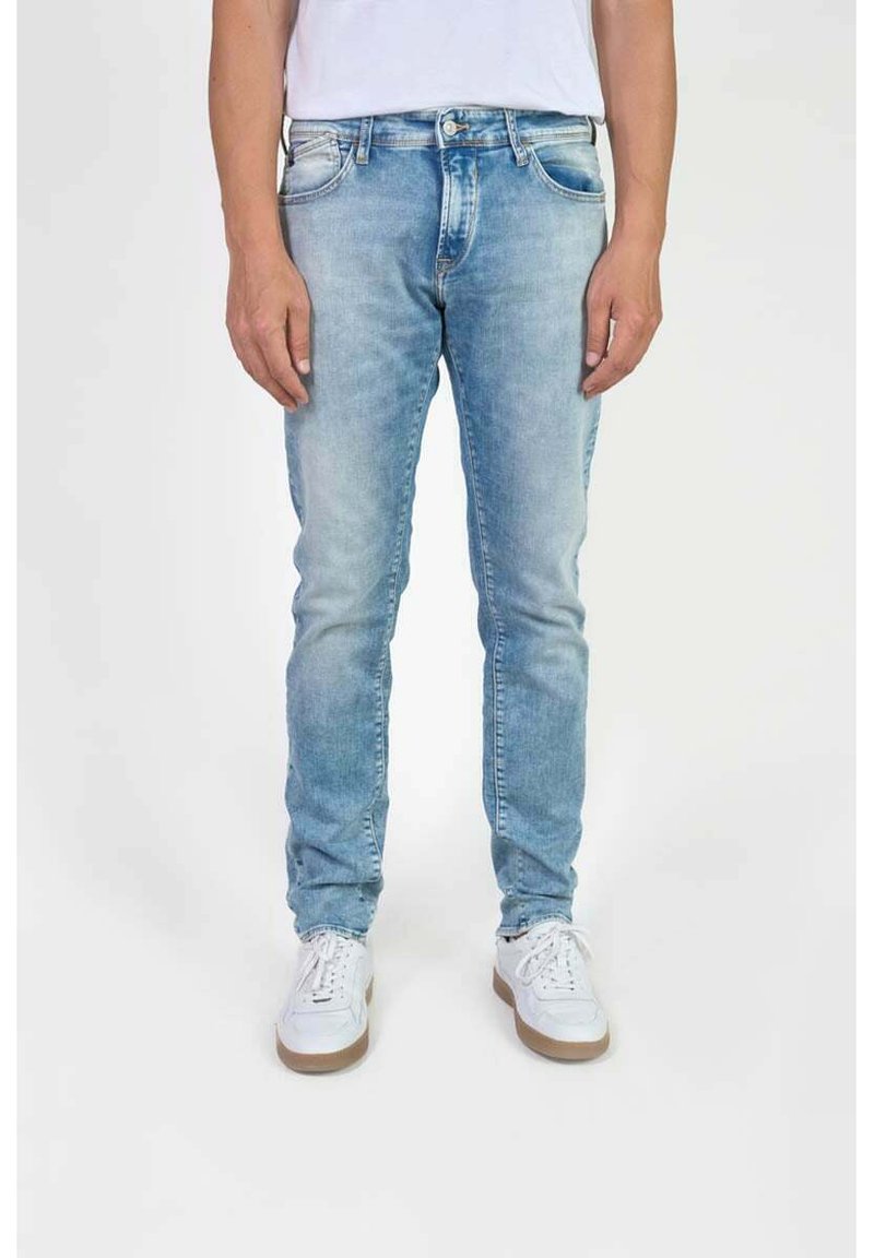 Lichtblauwe denim jeans met een slim fit, voorzien van zijzakken, een ritsluiting en een subtiele vervaagde wassing. Gecombineerd met witte sneakers.