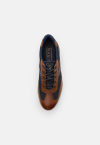 Brown leather and navy mesh sneaker with black laces and accents. Features a textured surface and logo detail on the tongue.