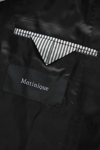 Mustat satiinist sisemised joped, millel on must silt kirjas "Matinique" ja must-valgete triipudega taskurätik rinna taskus.