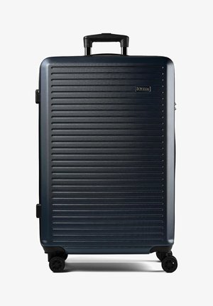 Großer dunkelblauer Hartschalenkoffer mit horizontalen Rillen, ausziehbarem Griff und vier schwarzen Drehrollen.