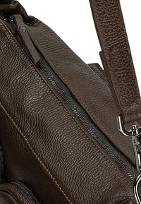 Borsa in pelle marrone con superficie testurizzata, zip nera e accessori metallici. Tracolla robusta con cuciture dettagliate.