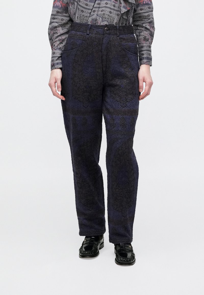 Tengerészkék mintás nadrág, texturált anyagból, egyenes szabású, elülső zsebekkel, fekete fényes cipőkkel párosítva.