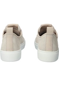 Baskets en daim beige avec une texture perforée, une semelle en caoutchouc blanche et un petit onglet au talon à l'arrière.