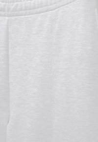 Gros plan sur un tissu gris clair avec une texture chinée subtile et un détail de couture verticale sur un vêtement doux.