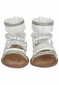 Sandales gladiateurs blanches avec plusieurs lanières, embellies d'accents en argent et de strass, présentant une semelle texturée et un soutien de la cheville.