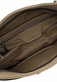 Beige handbag interior with multiple pockets, including zippered compartments and a soft lining. Stitched detailing and logo visible.