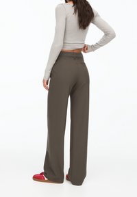 Gray long-sleeve top, high-waisted, olive-green wide-leg trousers, and red sneakers with brown soles. Smooth fabric with a tailored fit.