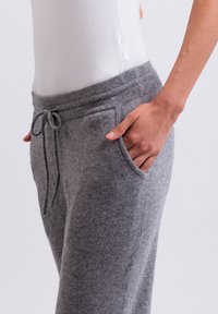 Graue Fleece-Jogginghosen mit elastischem Bund, Kordelzug und seitlichen Taschen. Weicher Stoff mit lässiger Passform.