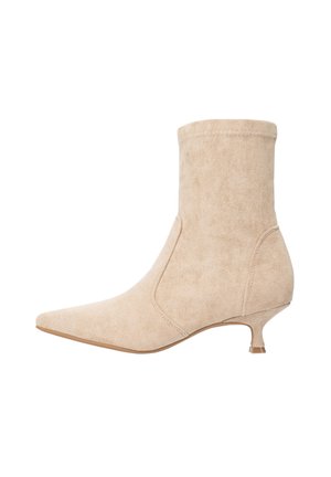 Bottine en daim beige avec un bout pointu et un petit talon kitten. Présente un design sans coutures et des coutures discrètes le long des bords.