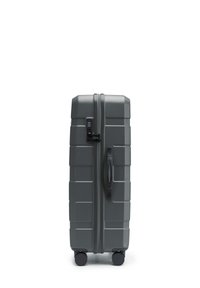 Maleta rígida gris con un acabado texturizado, asa superior, cerradura de combinación y cuatro ruedas giratorias. Forma rectangular con líneas horizontales.