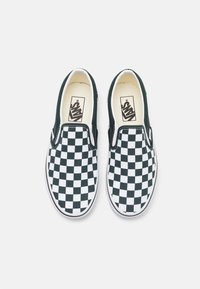Chaussures Vans slip-on à motif damier noir et blanc, avec semelles intermédiaires blanches et bordures noires, vues de dessus.