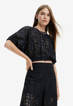 Zwart cropped top van kant met bloemmotieven, ronde halslijn en korte puffmouwen, gecombineerd met bijpassende kanten broek.