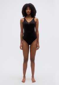 Μαύρο κορμάκι με δαντέλα στην κορυφή, σχέδιο με V λαιμόκοψη και ρυθμιζόμενες τιράντες, κατασκευασμένο από λείο, ελαστικό ύφασμα, εφαρμοστή γραμμή.