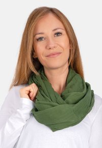Grüner, leichter, zerknitterter Schal, locker um den Hals gewickelt, der teilweise ein weißes Langarmshirt bedeckt. Einfaches Design, ohne Muster.