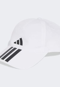 Gorra blanca de tela con diseño de tres franjas negras en el visor y un logo negro en la parte frontal. Visera curva y forma estructurada.