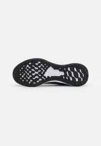 Suela de goma negra con patrón texturizado, entresuela blanca y sección superior de color claro que combina materiales para ofrecer adherencia y comodidad.