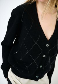 Cardigan nero lavorato a maglia con scollo a V profondo, caratterizzato da un motivo a diamante in filo grigio e cinque bottoni azzurri lungo il davanti.