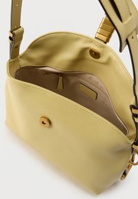 Κίτρινη δερμάτινη τσάντα χειρός με επίπεδο σχήμα, που διαθέτει μαγνητικό κλείσιμο, εσωτερική τσέπη με φερμουάρ και κομψό ρυθμιζόμενο λουρί.