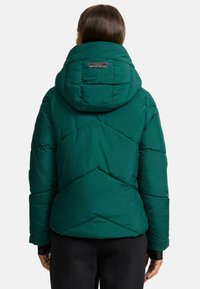 Green puffer jacket with a high collar and hood, featuring a diamond quilted pattern and a logo tag at the back. Soft texture.