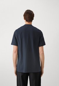 Camiseta de algodón azul marino con mangas cortas, corte recto y un sutil detalle de costura en la parte posterior. Sin logotipos ni patrones visibles.