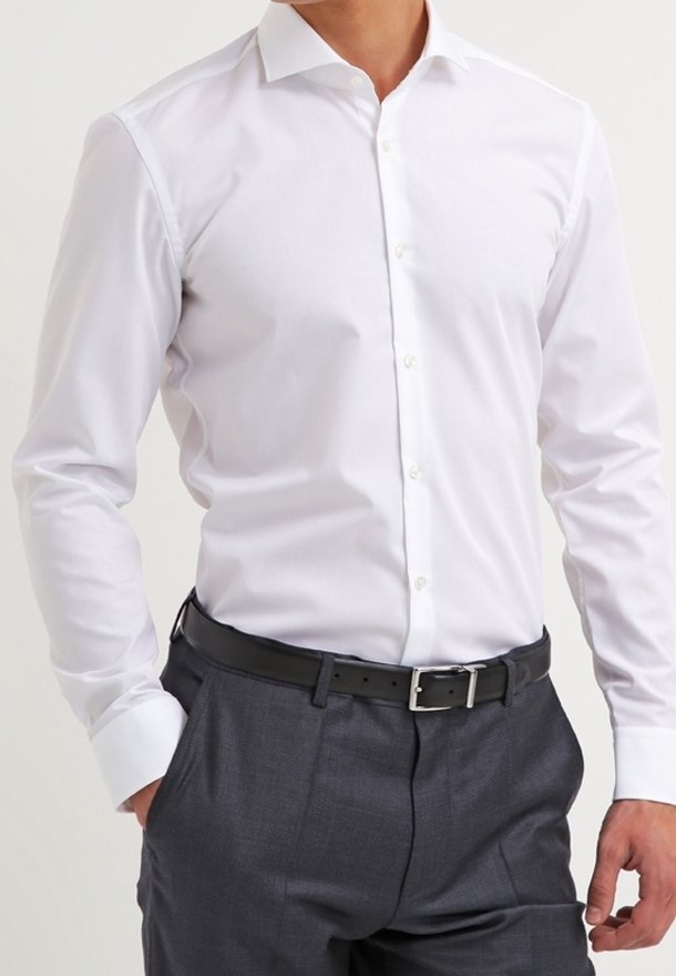 Biała koszula na guziki z spiczastym kołnierzykiem, długimi rękawami i gładką tkaniną. W połączeniu z szarymi spodniami i czarnym paskiem.