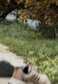 Light brown athletic shoe with black accents, textured sole, set on a path surrounded by green grass and foliage.