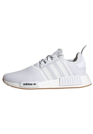 Baskets blanches Adidas NMD avec trois bandes, semelle texturée et semelle extérieure couleur gomme, vues de profil sur fond blanc.