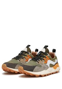 Sneaker verde e marrone con accenti arancioni; tessuto texturizzato, linguetta imbottita, lacci neri e una suola spessa distintiva.
