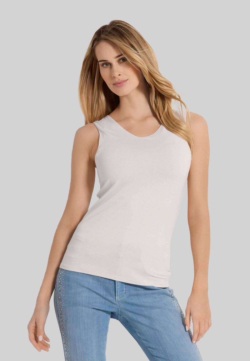 Witte mouwloze top met een ronde hals, gemaakt van zachte stof. Gecombineerd met lichtblauwe jeans met decoratieve naden.