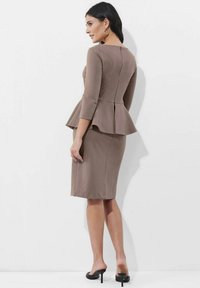 Peplum-Kleid aus taupefarbenem Stoff, mit Dreiviertelärmeln und schmalem Bleistiftrock. Weiche Textur mit einem Reißverschlussdetails auf dem Rücken.
