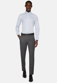 Ljusblå skjorta med knappar i kombination med grå skräddarsydda byxor. Outfiten har en elegant design, subtil textur och ett bälte i svart läder.