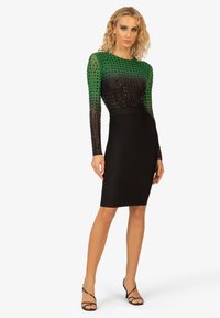 Zwart midi-jurk met een aansluitende silhouet, featuring een groen en zwart gestippelde doorschijnende top en lange mouwen. Elegante textuurontwerp door het hele kledingstuk.