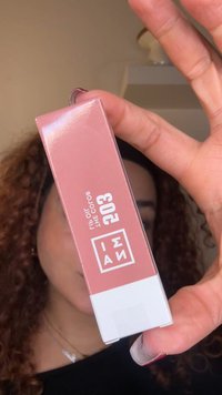 Confezione di rossetto in una scatola rosa opaca con fondo bianco. Presenta un testo in grassetto "I AM" e il numero della tonalità "203" ben visibili.