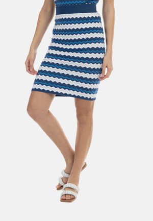 Strikket nederdel med zigzag-mønstre i blå og hvid, med en tætsiddende facon og ribkant i taljen. Sammen med flade, strappy hvide sandaler.
