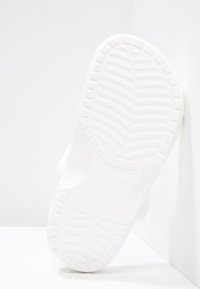 Semelle de chaussure en caoutchouc blanc présentant un motif de bande de roulement texturé et des rainures surélevées pour la traction. Bords lisses et design minimaliste.