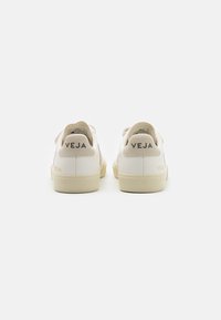 Baskets en cuir blanc avec des accents en suède beige. Logo "VEJA" en noir au niveau du talon. Bout arrondi et semelle en caoutchouc texturée. Design épuré.
