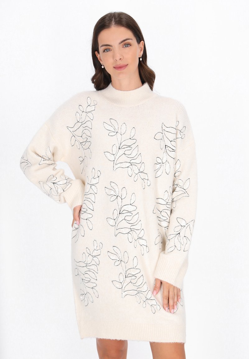 Rochie tricotată de culoare crem cu guler înalt, prezentând broderie florală neagră, mâneci oversized și manșete și tiv cu nervuri.