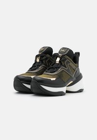 Schwarze und goldene Sport-Sneaker mit einem oberen Teil aus Mesh, strukturierten Einsätzen, einer dicken weißen Sohle und metallischen Akzenten sowie schwarzen Schnürsenkeln.