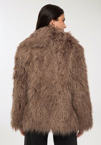 Giacca in pelliccia sintetica marrone con una trama shaggy e un design ampio, dotata di colletto alto e maniche lunghe.