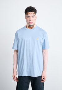 Light blue cotton T-shirt featuring a round neckline and short sleeves, with a small yellow logo on the left chest area.