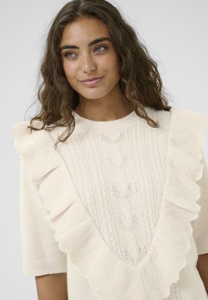 Maglione lavorato a maglia color crema con scollo a V profondo bordato di volant, maniche corte e dettagli intricati a trecce sul davanti.