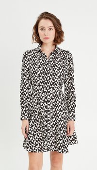 Abito button-up bianco e nero con motivi geometrici, maniche lunghe e vita aderente, che si allarga in una gonna svasata all'orlo.