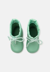 Bottes imperméables vert menthe avec un col doux et rembourré, des lacets texturés et un extérieur lisse. orteils ronds et semelle intérieure rembourrée.