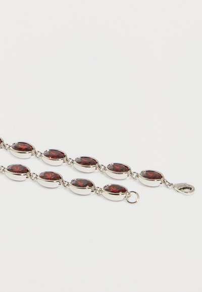 Srebrna zapestnica z ovalnimi rdečimi dragimi kamni, povezanimi z majhnimi obročki, s karabinom in okroglim pritrdilnim obročkom na belem ozadju.