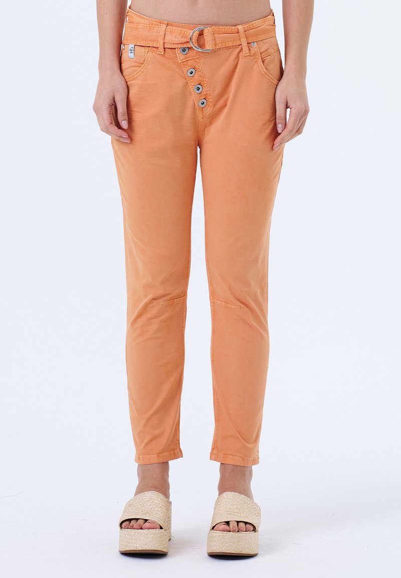 Pantalon en coton mélangé orange avec un zip à cinq boutons, poches avant et une coupe slim. Associé à des sandales à plateforme tissées.