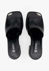 Zwarte slidesandalen met een vierkante teenontwerp, featuring een bovenkant van soepel leer en een metallic logo detail. Gedefinieerde, lage blokhak.