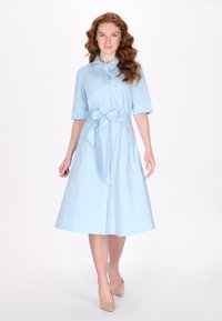 Hellblaues, kurzärmeliges Hemdkleid mit Kragen und Taillenzug. Glattes Material mit einem ausgestellten Rock und Knopfleiste.