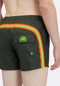 Costumi da bagno verde scuro con strisce laterali arancioni e verdi, una tasca posteriore con un'etichetta logo e un piccolo foro verde decorativo.